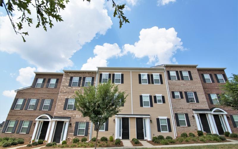 Exterior view of three-story red brick building at Charleston Row luxury townhomes in Charlotte, NC